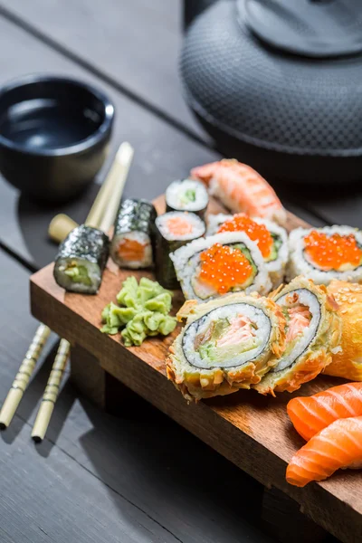 Sushi fresco em tábua de madeira servida com chá — Fotografia de Stock