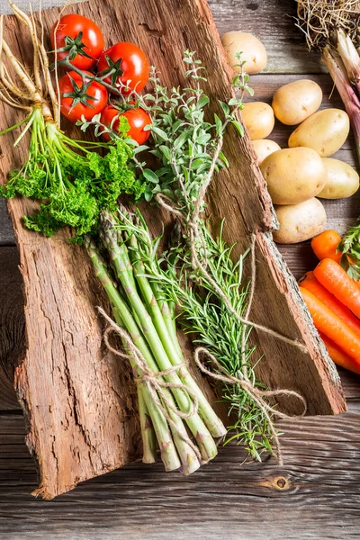 Färska olika grönsaker på bark — Stockfoto