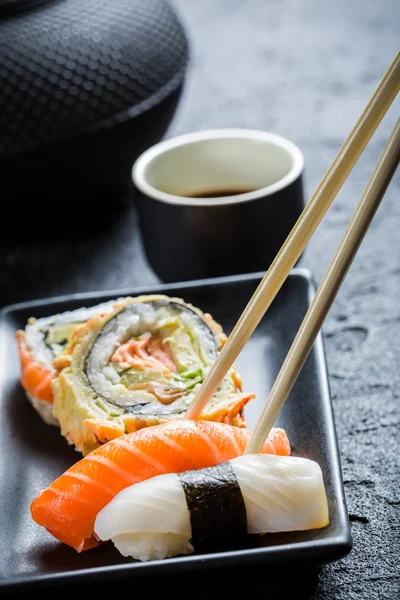 Sushi in schwarzer Keramik mit Essstäbchen — Stockfoto