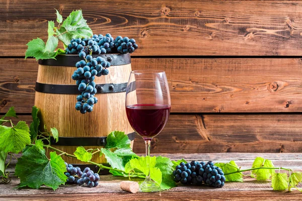 Pohár vörös bor és a szőlő, egy fából készült pincében — Stock Fotó