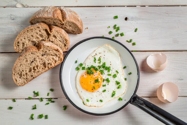 Fried egg with chives served with bread — Stock Photo, Image