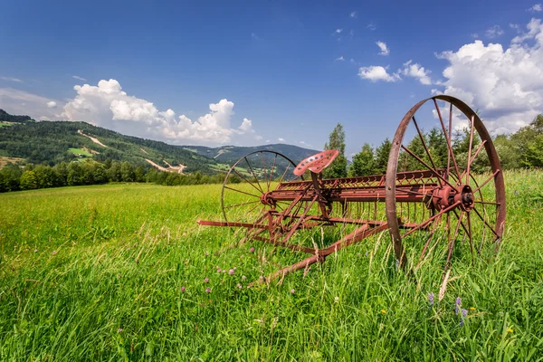 Red rake in a field in the mountains — Stock Photo, Image