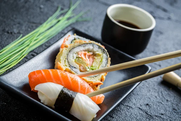 Sushi in een zwarte keramische gegeten met stokjes — Stockfoto