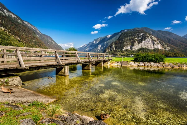 Puente de madera sobre el río entre montañas — Foto de Stock