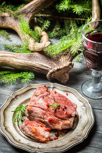 Pièce de venaison servie avec du vin rouge — Photo