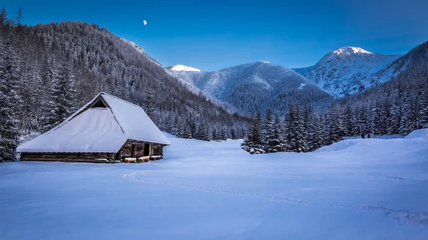 Невеликий гірський котедж в зимовій долині на заході сонця — стокове фото