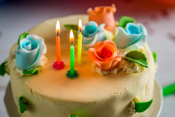 Beautiful birthday cake with lighted candles and marzipan roses — Stock Photo, Image