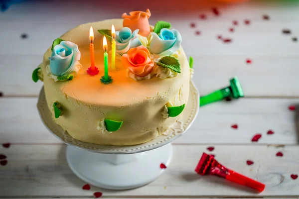 Sweet birthday cake with lighted candles and marzipan roses — Stock Photo, Image