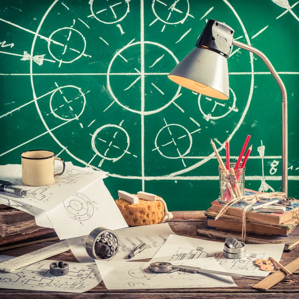 Mechanical engineer desk at the school on green chalkboard background