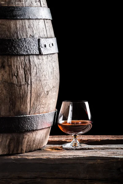 Glass of cognac and old oak barrel — Stock Photo, Image