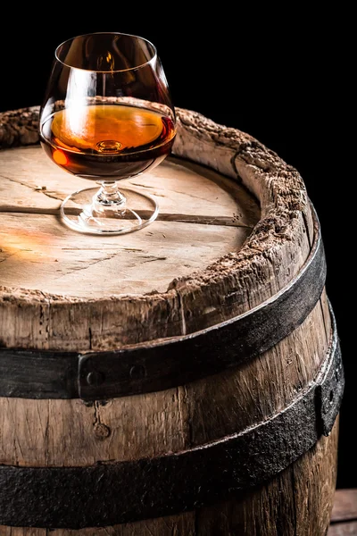 Glass of aged cognac and old wooden barrel — Stock Photo, Image