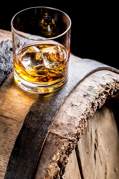 Whiskey glass with ice on old oak barrel — Stock Photo, Image
