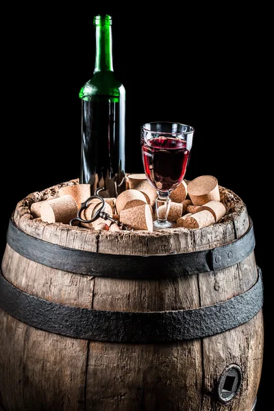 Copo de vinho tinto e uma garrafa em pé sobre um barril — Fotografia de Stock