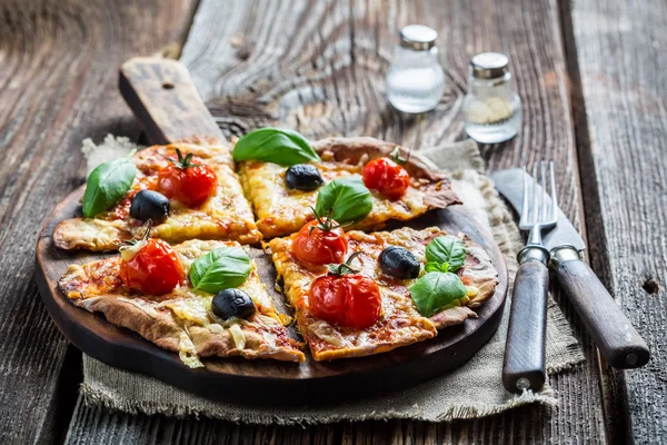 Fresh pizza on paper and old wooden table — Stock Photo, Image