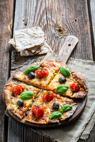 Pizza fresca em papel e mesa de madeira velha — Fotografia de Stock