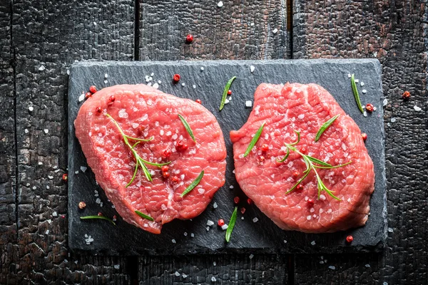 Pedaço de carne bovina com alecrim e pimenta em um prato de pedra — Fotografia de Stock