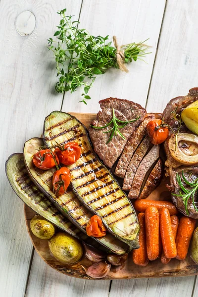 Rostade grönsaker och biff med salt på vitt bord — Stockfoto