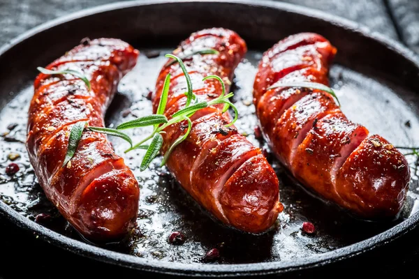 Salchicha a la parrilla con romero fresco en el plato de barbacoa caliente —  Fotos de Stock