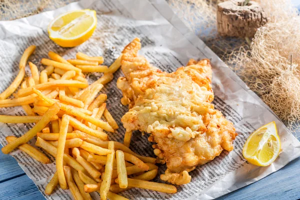 Bacalhau de peixe saboroso com batatas fritas servido em papel — Fotografia de Stock