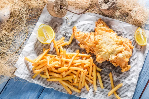 Peixes frescos e batatas fritas servidos em papel — Fotografia de Stock