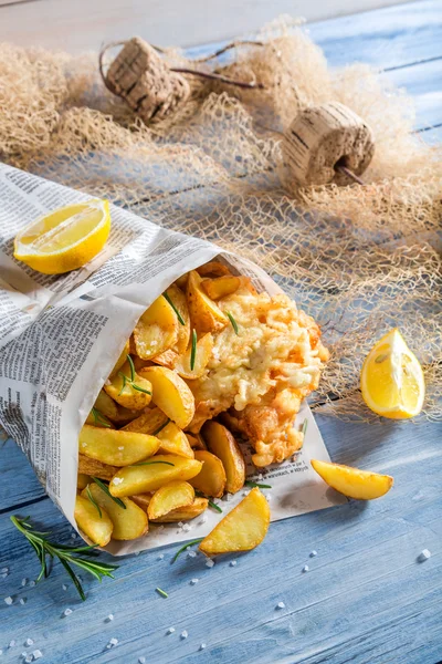 Sabroso pescado y patatas fritas en el periódico con limón — Foto de Stock