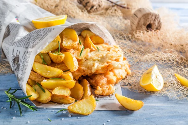 Sabroso pescado y patatas fritas servidas en papel con limón — Foto de Stock