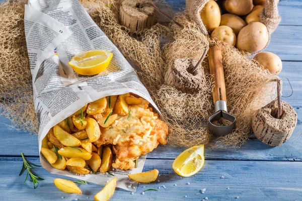 Frischer Kabeljau mit Pommes in Papier mit Zitrone serviert — Stockfoto