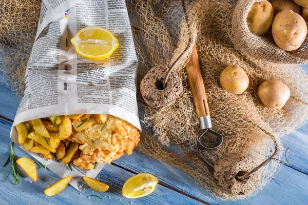 Pesce e patatine fatte in casa servite in carta con limone — Foto Stock