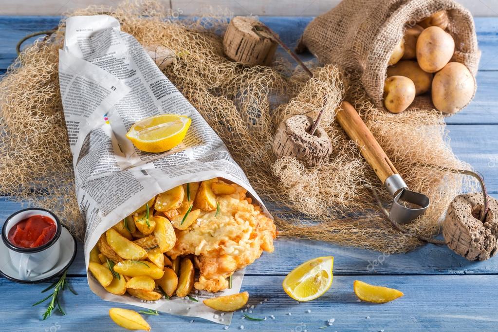 Tasty fish cod with chips in newspaper with lemon — Stock Photo