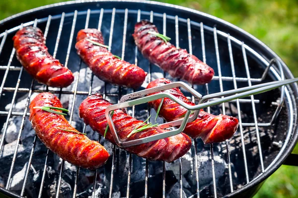 Spicy sausages with spices and rosemary on a grill — Stock Photo, Image