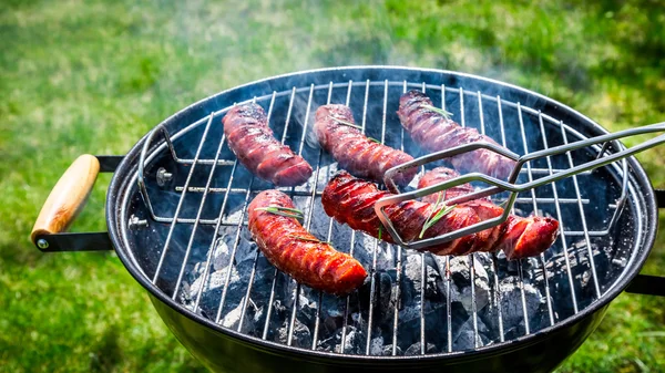 Salchichas picantes con especias y romero en la parrilla del jardín — Foto de Stock