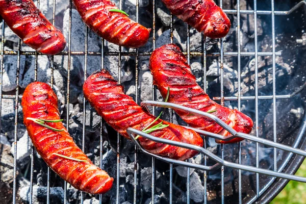 Geroosterde worstjes met specerijen en rozemarijn op een grill — Stockfoto