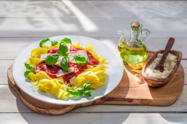 Pappardelle pasta with tomato sauce and basil in the sunny kitchen clipart