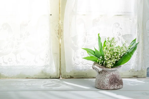 Lily of the valley in een vaas in de buurt van een zonnige venster — Stockfoto