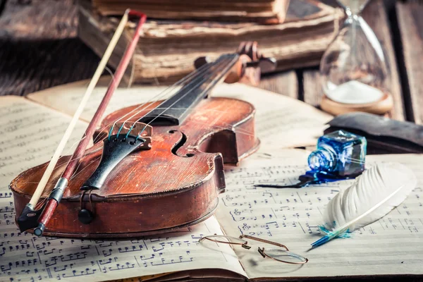 Sábanas musicales retro y violín sobre mesa de madera vieja — Foto de Stock