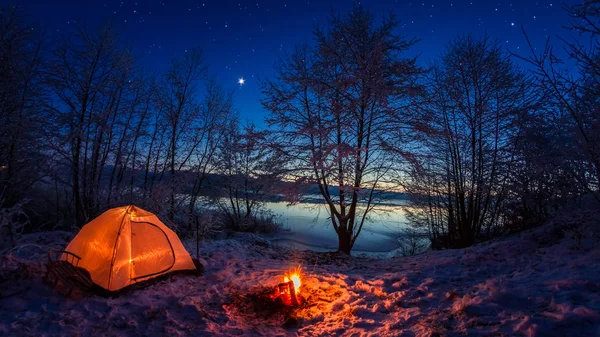 Tenda illuminata nel campo invernale vicino al lago di notte — Foto Stock