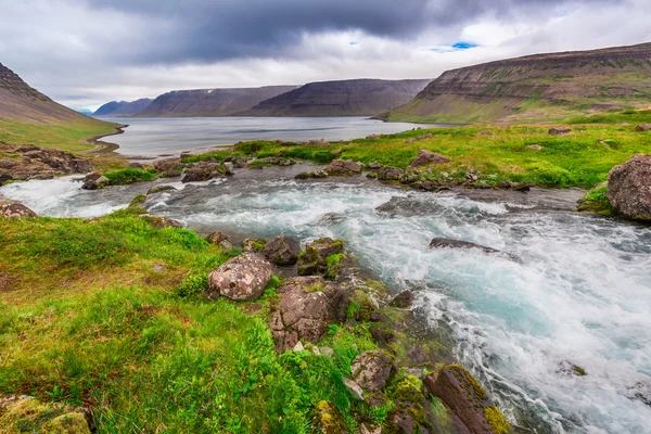 Mountain floden flyter in i sjön mellan bergen i Island — Stockfoto