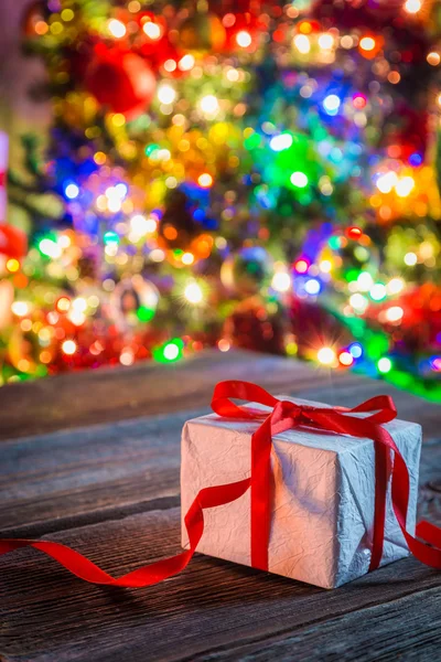 Wunderschönes Weihnachtsgeschenk mit Baum und Lichtern im Hintergrund — Stockfoto