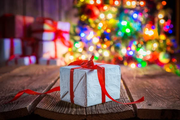 Tradizionalmente regalo di Natale con albero e luci sullo sfondo — Foto Stock