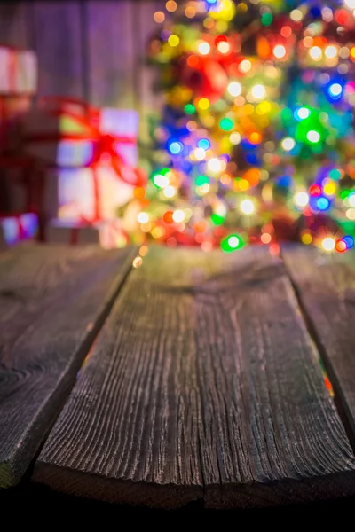 Fondo de Navidad con mesa de madera vieja, bokeh luz y regalos . — Foto de Stock