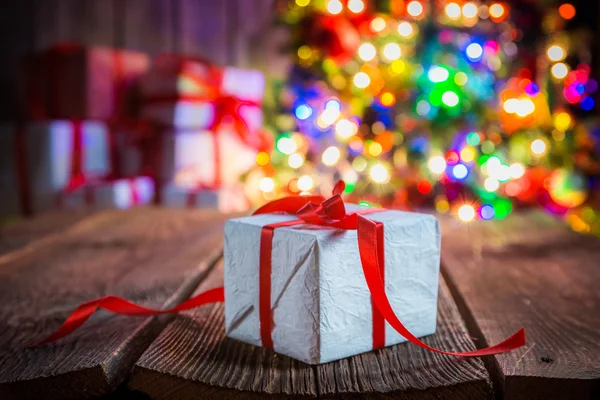 Традиційно різдвяний подарунок з деревом і вогнями на фоні — стокове фото
