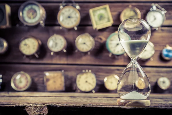 Gamla timglas på bakgrund av klockor — Stockfoto