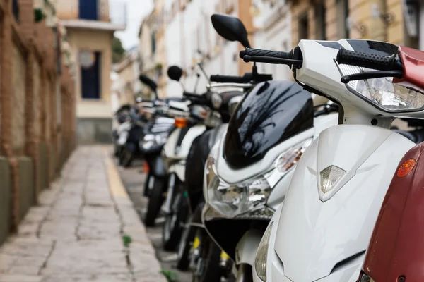 Many mopeds and motorbikes parked next to the sidewalk — Stock Photo, Image