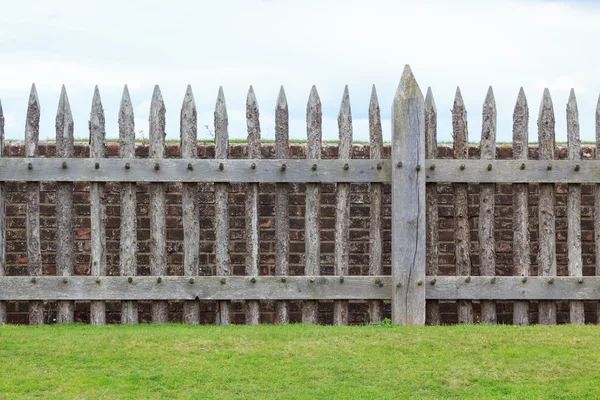 Wooden fence in front of brick wall — Stock Photo, Image