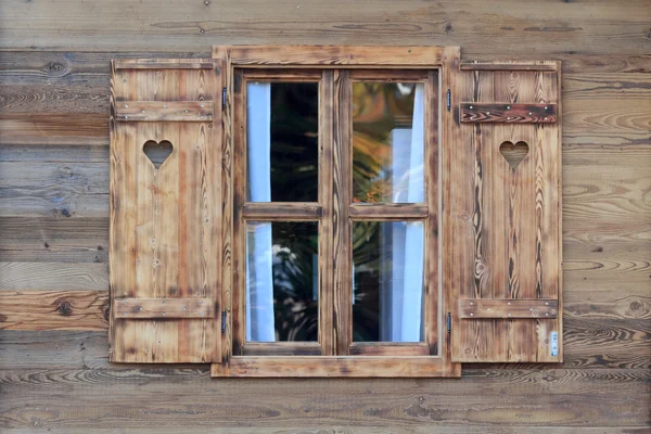 Fenêtre d'une cabane en bois avec des cœurs dans les stores — Photo