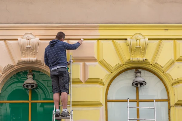 En målare måla en gammal fasad Stockbild