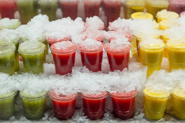 Soğuk, taze kivi, berry ve ananas meyve suyu plastik kap içinde