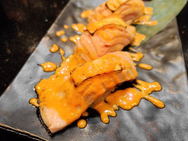 Gri taştan tabakta servis edilen füzyon somon suşisi setine yakından bakın. Füzyon Japon mutfağı