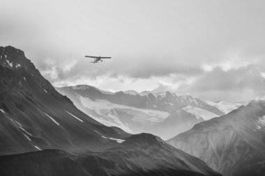Small plane in big mountains clipart