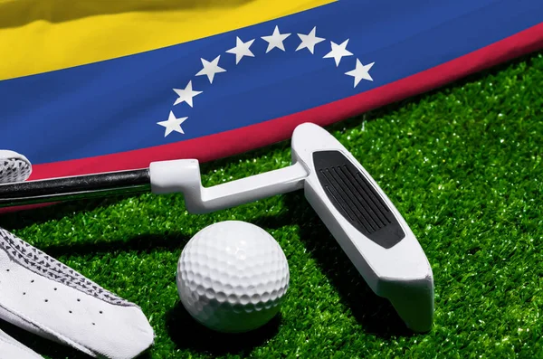 Golf ball and club with flag of Venezuela on green grass. Golf championship in Venezuela